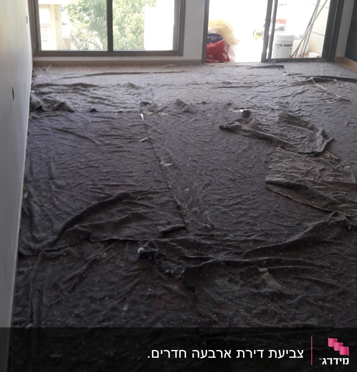 יריעות בד מכסות רצפה בחדר לקראת צביעה